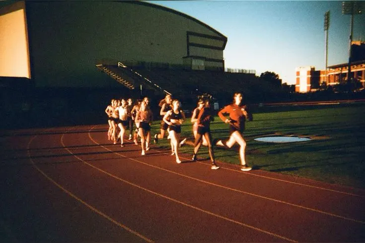 Runners on an athletics track at golden hour, shot on film